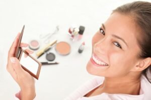 Femme souriante avec des produits de maquillage et un miroir